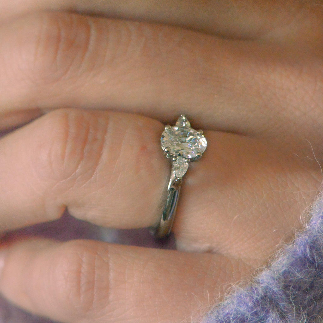 Diamond trilogy ring on a finger with a blurred background