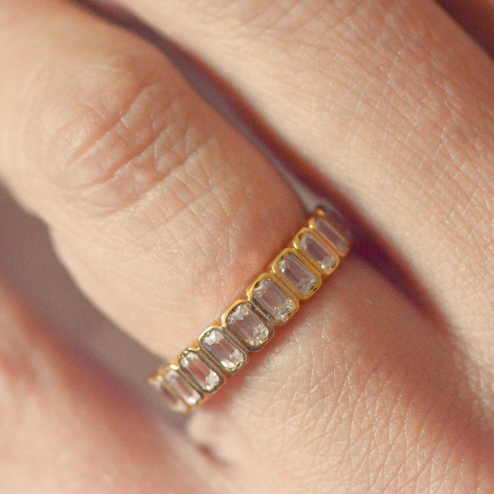 Art deco inspired gold wedding band with emerald cut diamonds on a person's finger