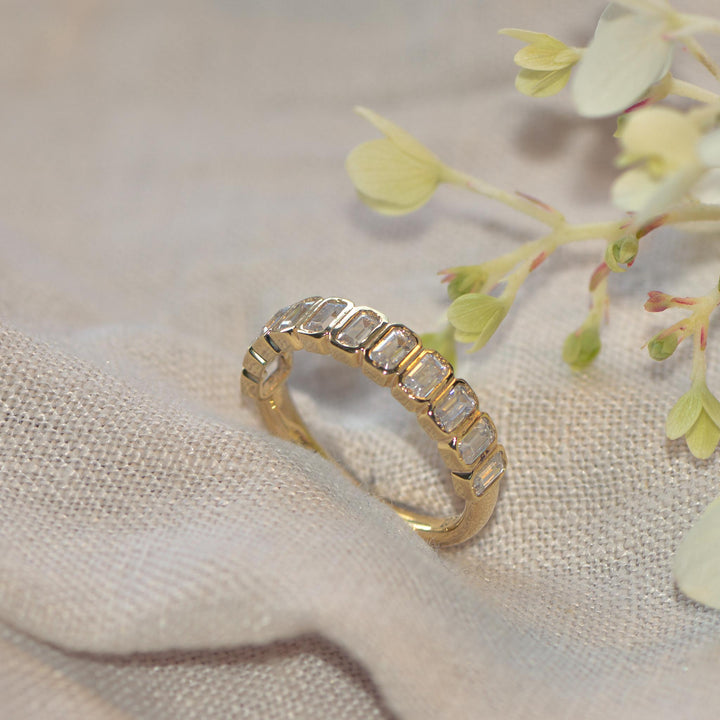 Gold ring with bezel set diamonds on a soft fabric background