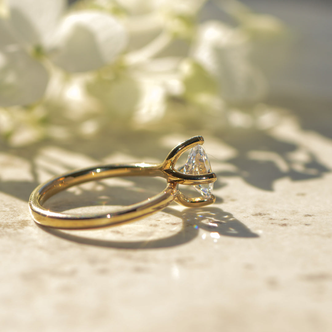 Gold solitaire engagement ring with a diamond on a light background