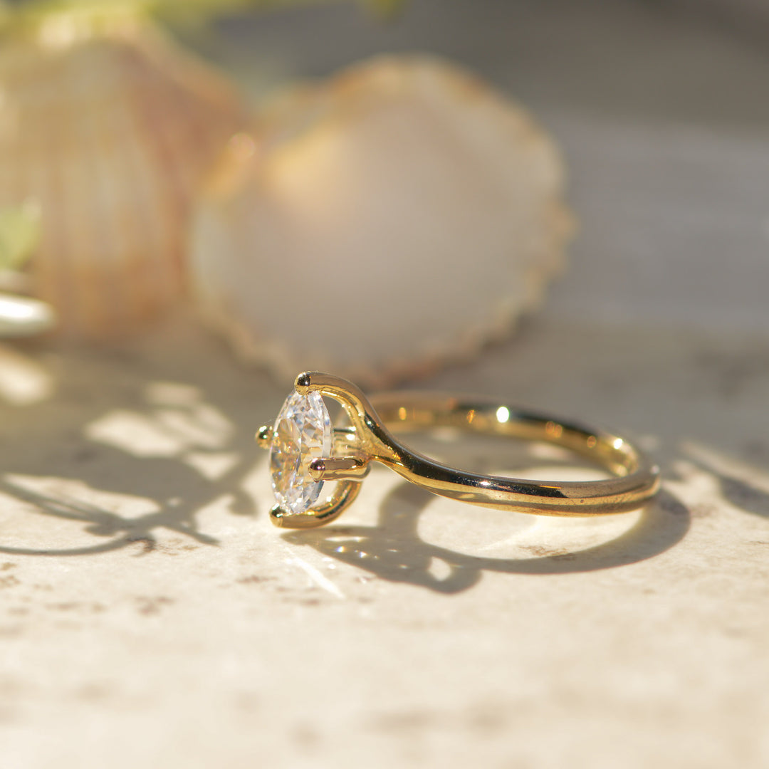 Gold oval ring with a diamond on a marbled surface