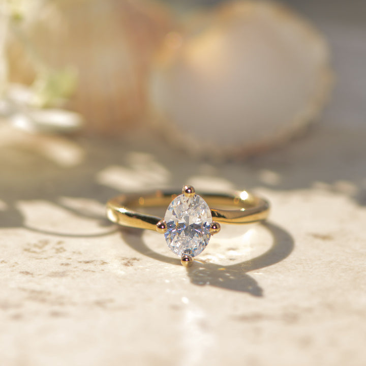 Oval cut gold engagement ring with a large diamond on a light background