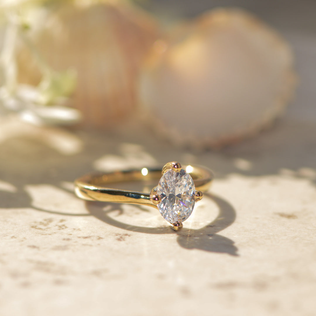Gold ring with a oval shaped diamond on a light background