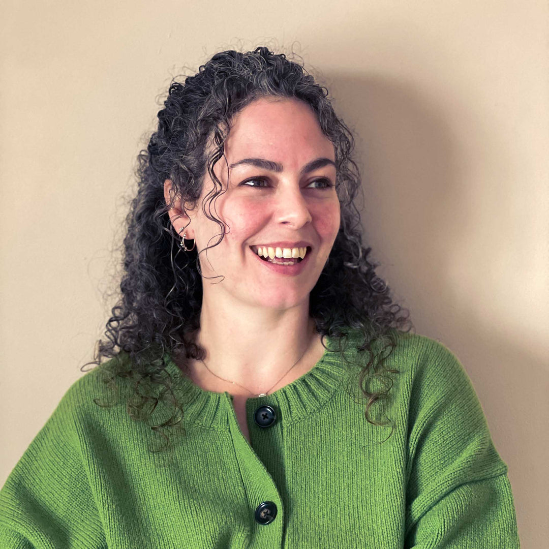 Woman wearing a green sweater against a beige background