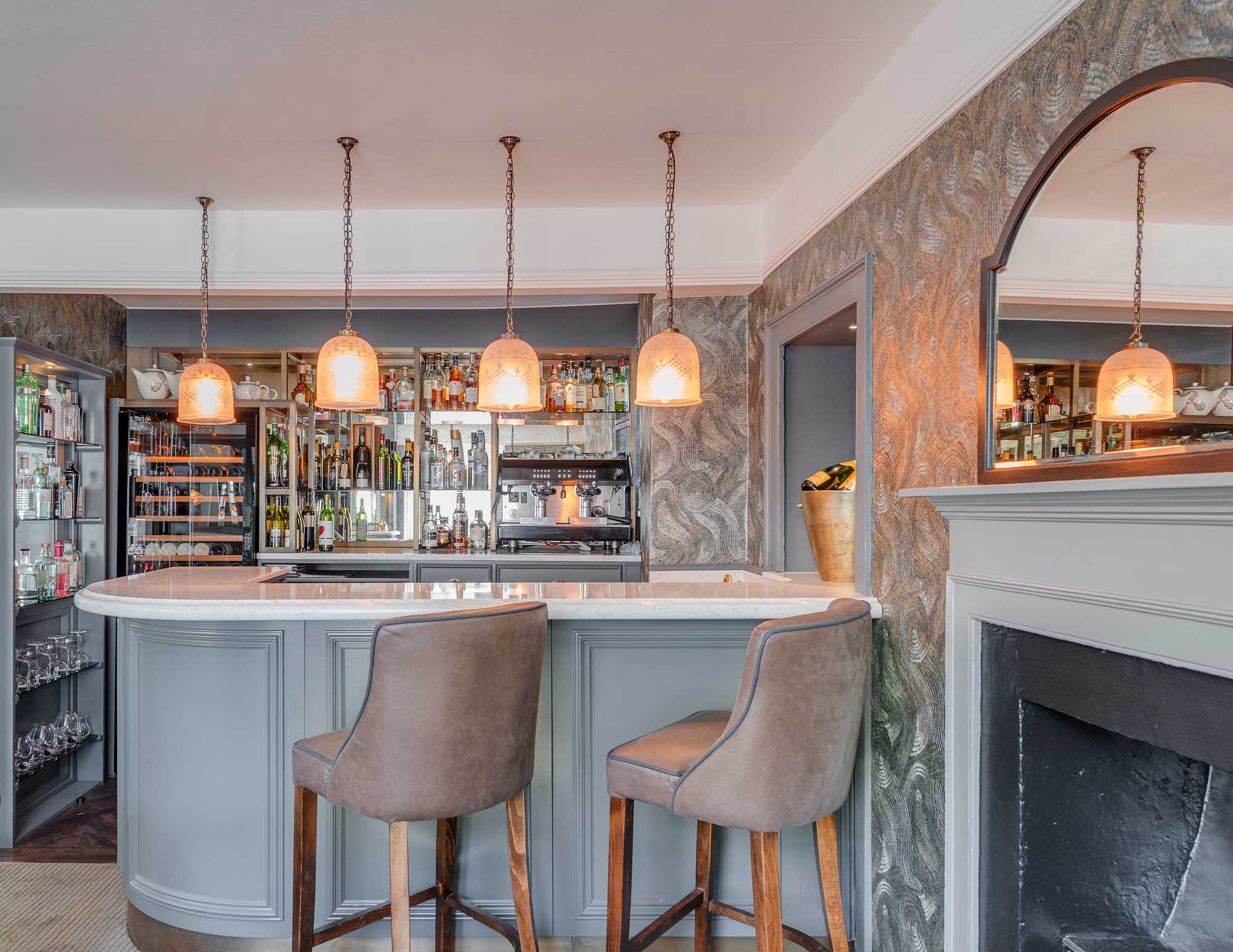 Bar area with bar stools, shelves, and a fireplace at Paul Ainswrth restaurant No. 6 Padstow.