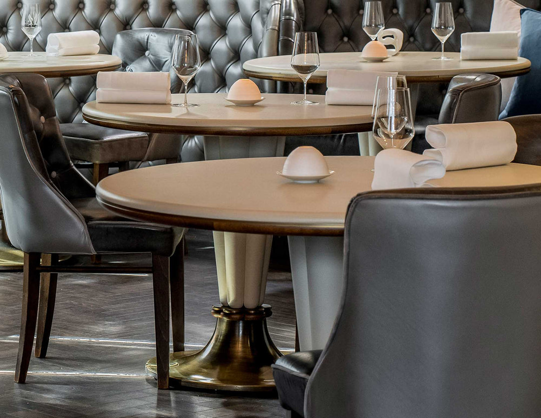 Dining area with round tables, chairs, and wine glasses in a restaurant setting.