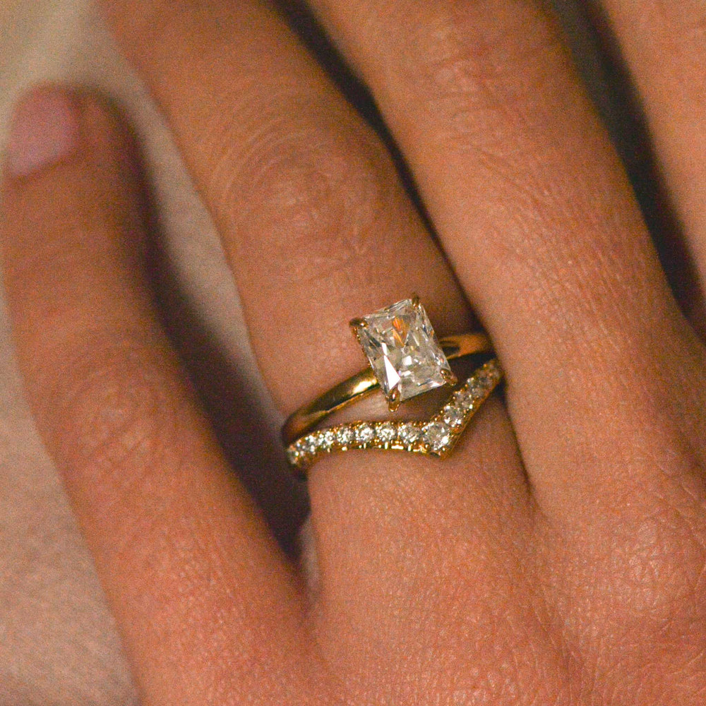 Radiant cut engagement ring in gold worn on the hand with a chevron diamond pavé wedding band