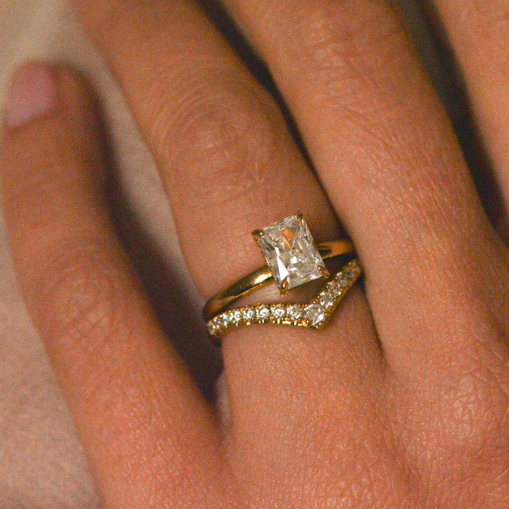 Radiant cut engagement ring in gold worn on the hand with a chevron diamond pavé wedding band