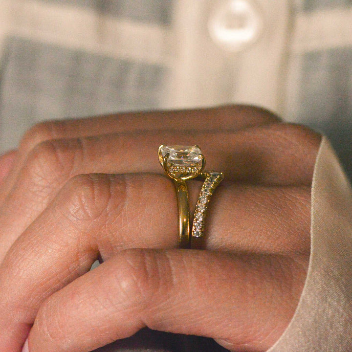 Side view of a hidden halo ring stacked with a pavé set wedding band worn on the hand