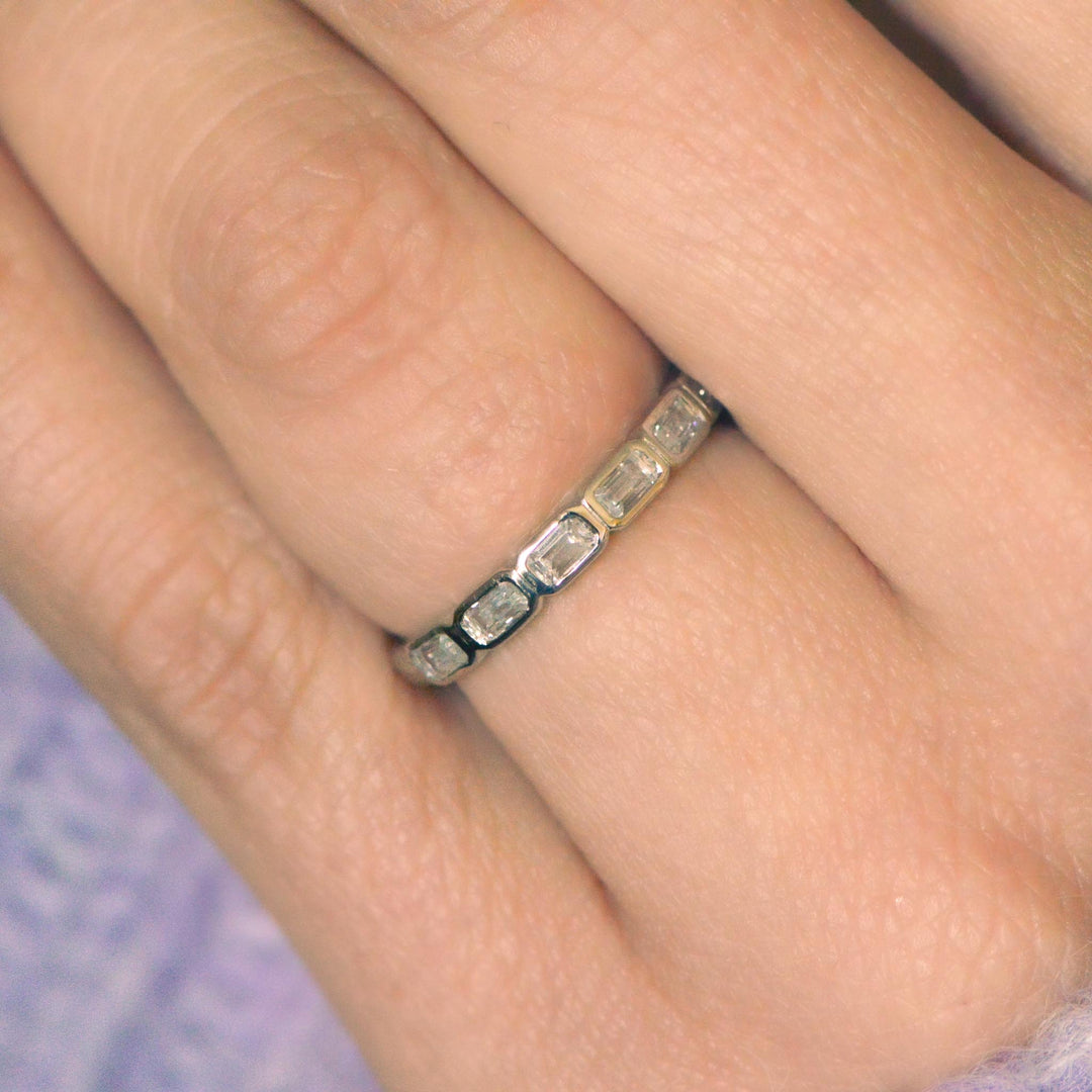 Platinum wedding band with east-west set emerald cut diamonds on a finger