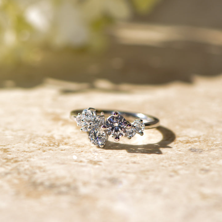 Cluster diamond platinum ring on a textured surface with a blurred natural background