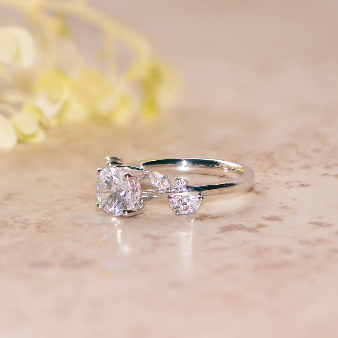 Platinum nature inspired ring with round cut diamond on a marble surface