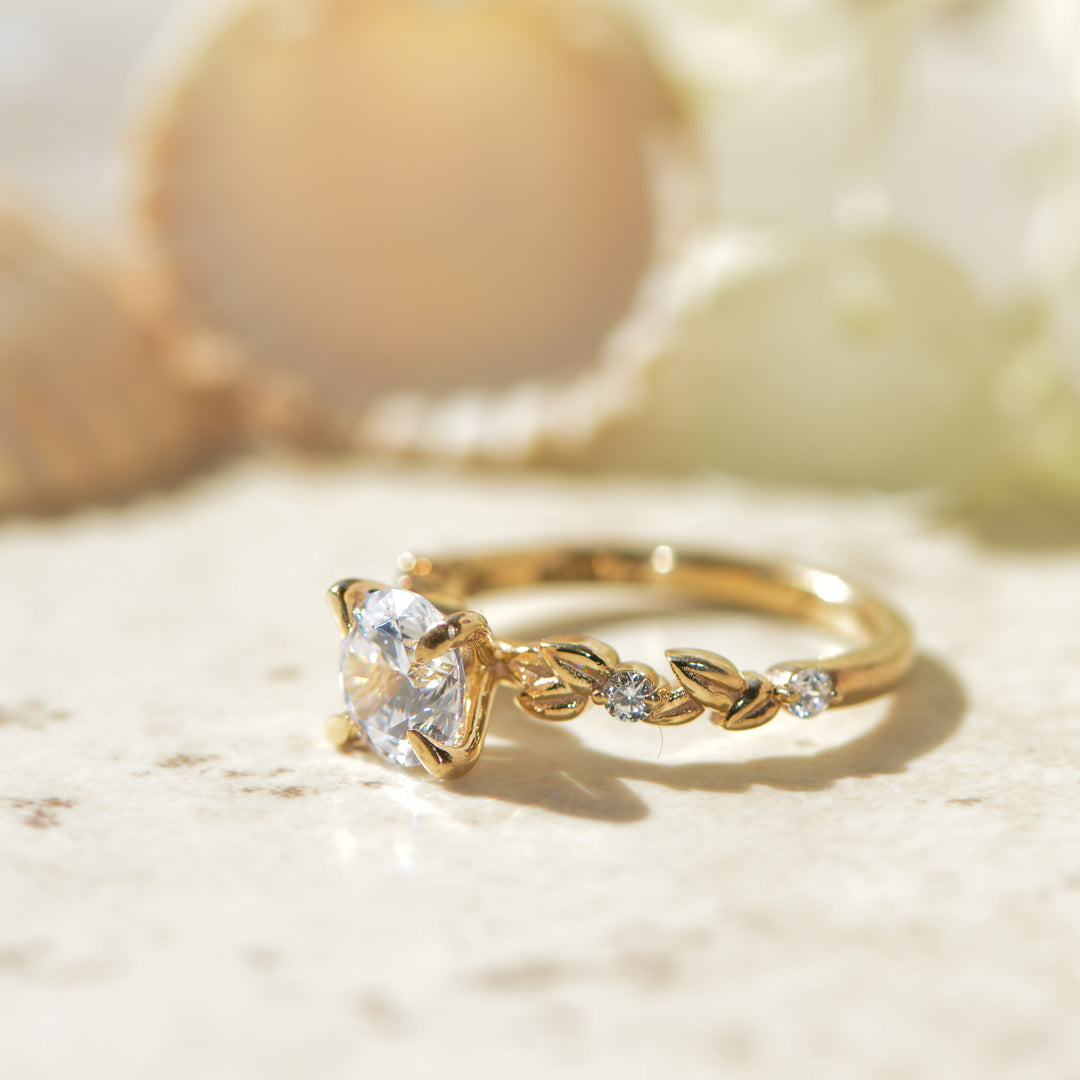 Gold ring with a diamond and a nature inspired band on a light background