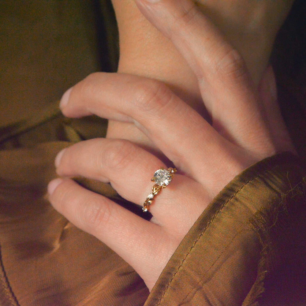 Close-up of a hand wearing a gold ring with a diamond on a brown background