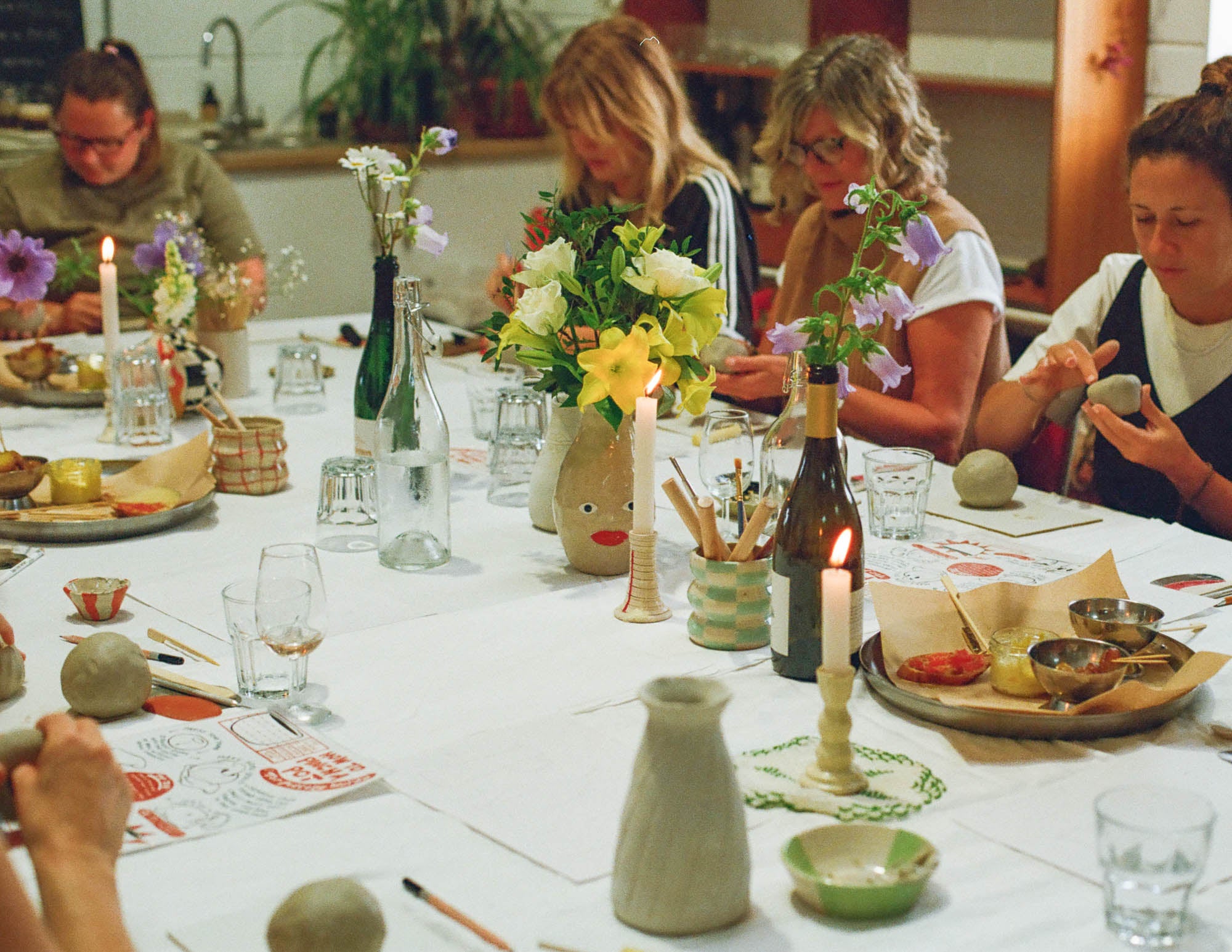 People sat at a table making ceramics during a group pottery course in a handmade pottery studio in Cornwall. 