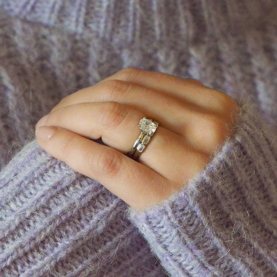Hand wearing a diamond ring on a textured purple sweater