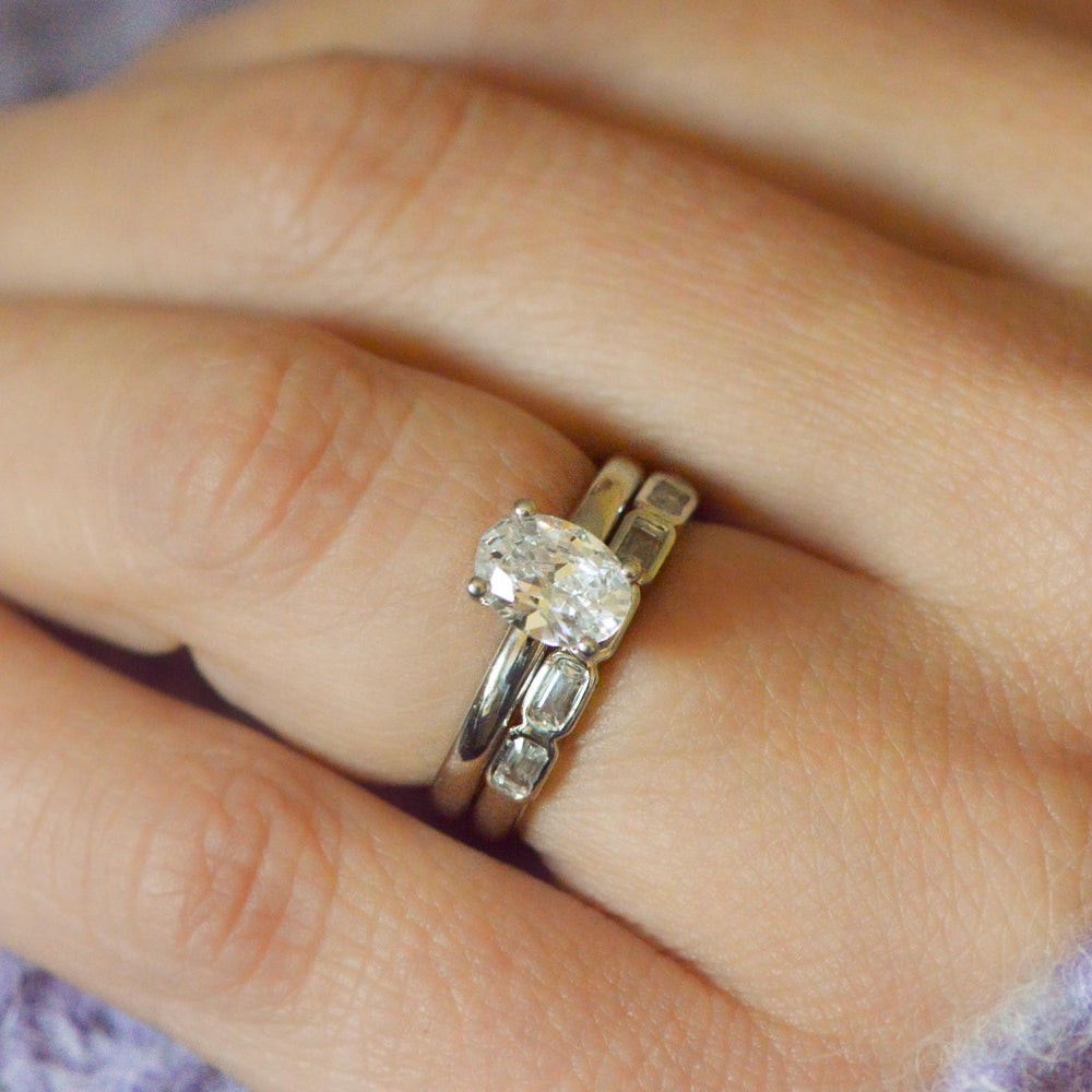 Close-up of a hand wearing two diamond rings on a blurred background