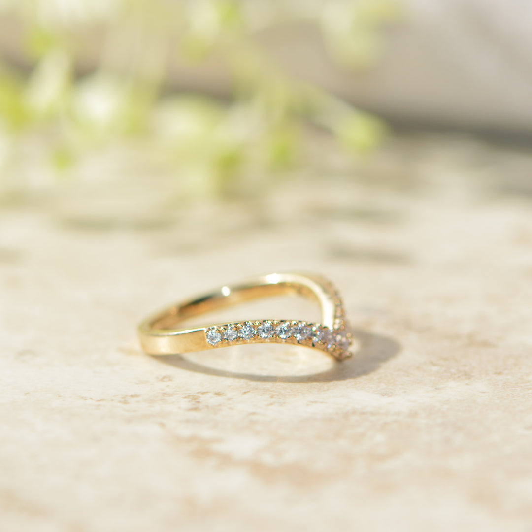 Gold ring with small diamonds on a light wooden surface