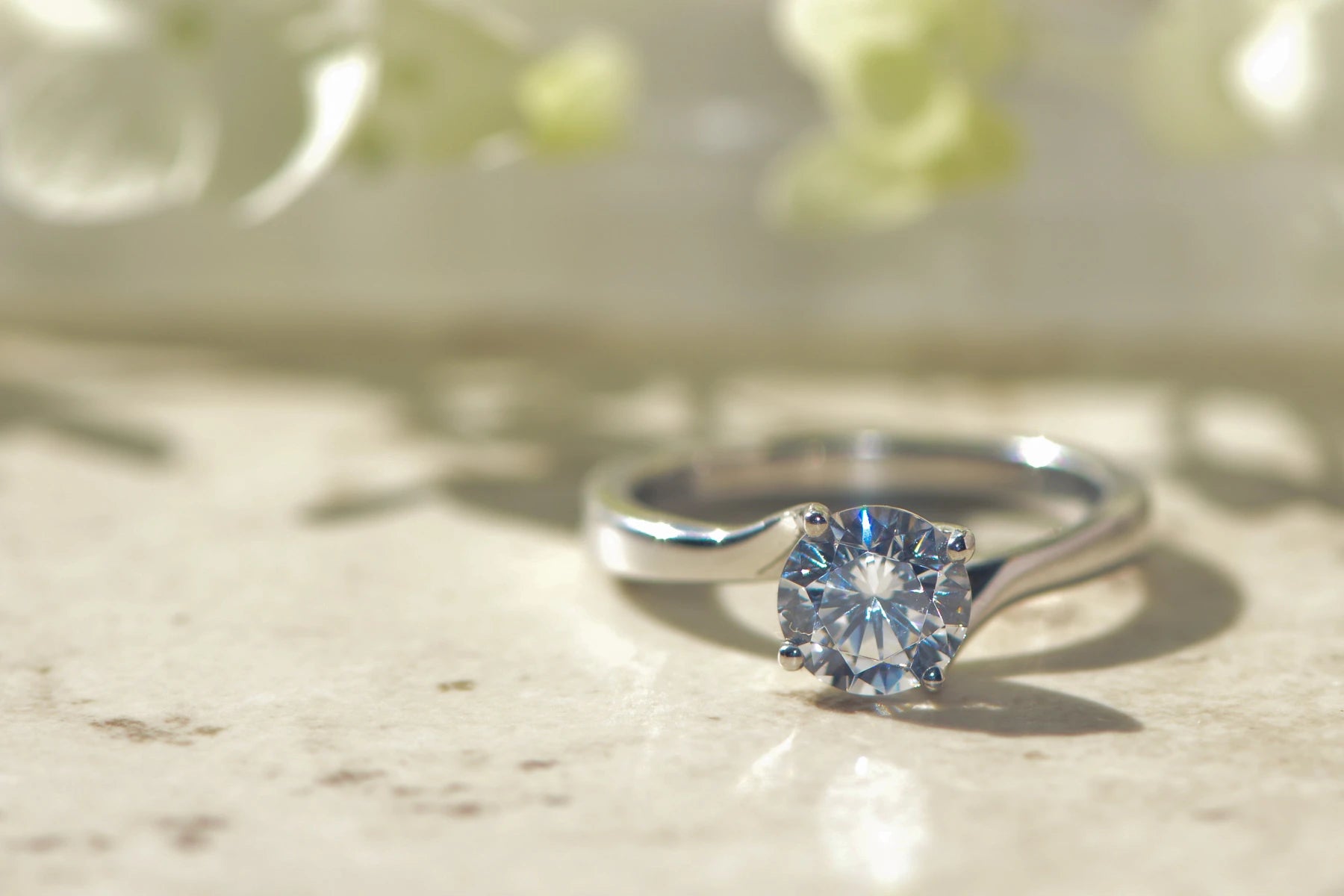 Round brilliant cut lab diamond engagement ring on a soft focus background 
