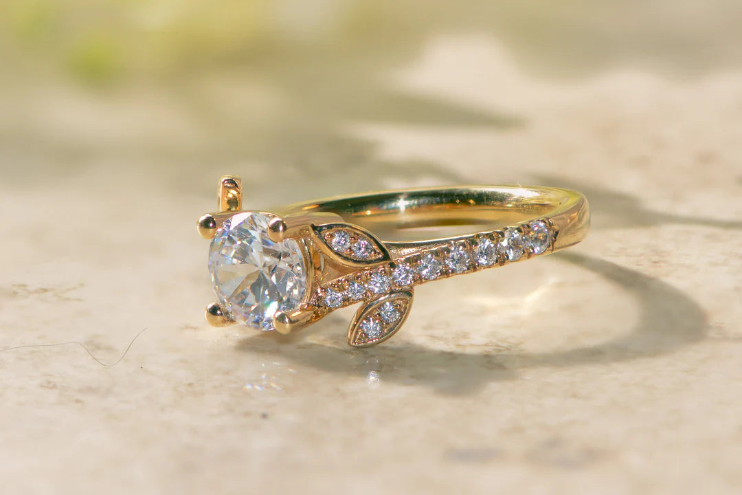 Close up of a nature inspired engagement ring with a diamond pave band in gold. 