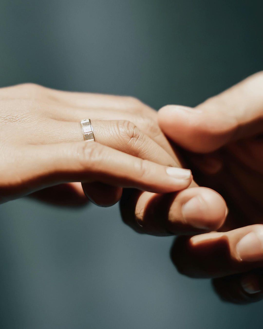 Two hands with a gold ring on a blurred background