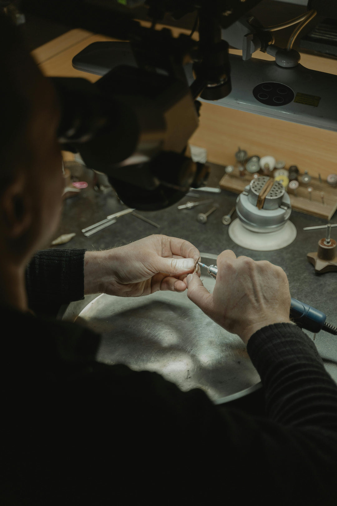 Person working with jewelry on a table with tools and materials