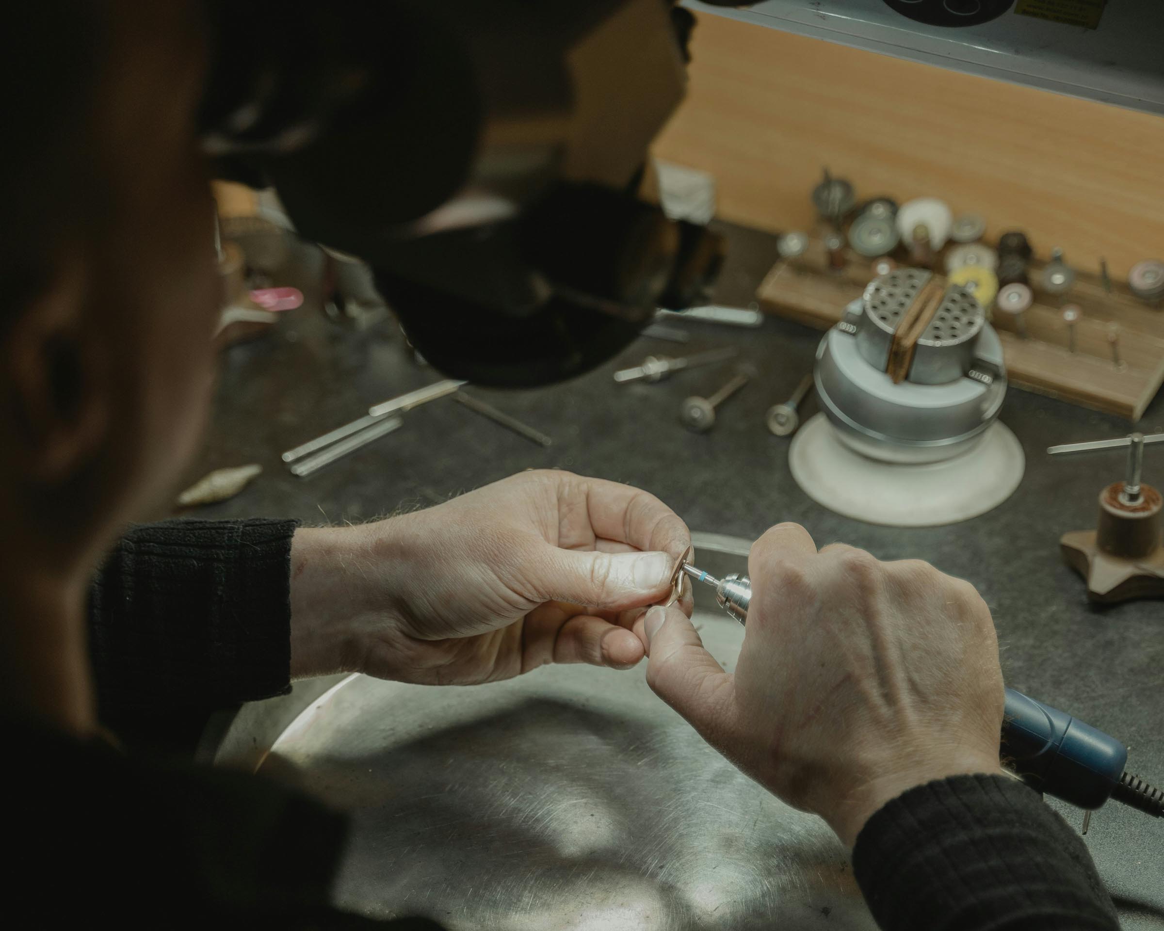 Person working on a piece of  jewellery with tools in a workshop setting